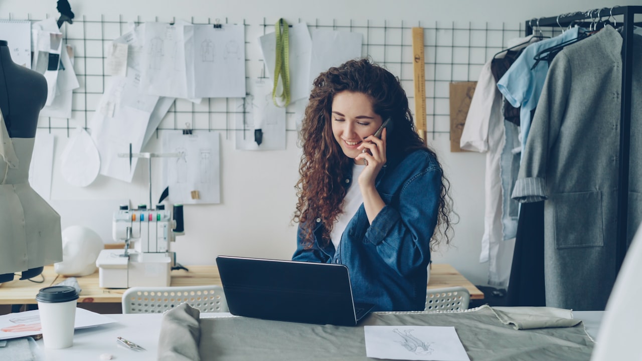 A business owner working on a laptop and phone at a desk