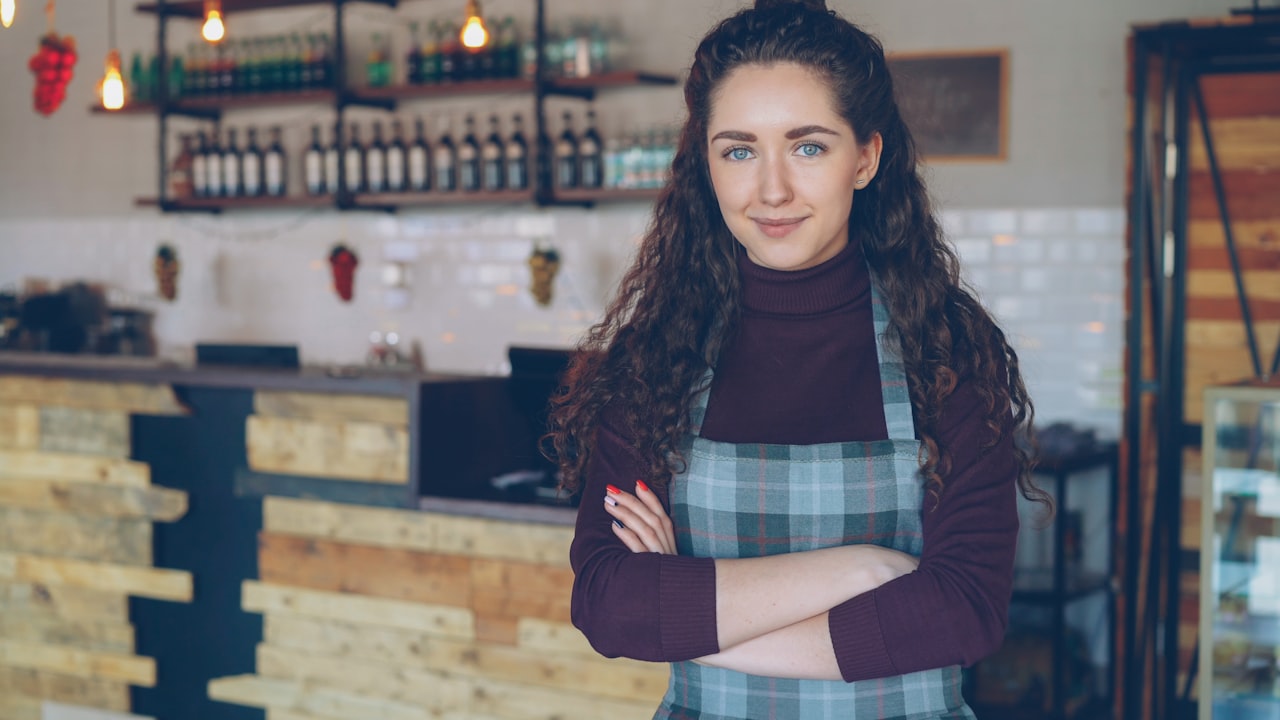 A smiling small-business owner standing behind the counter of her shop