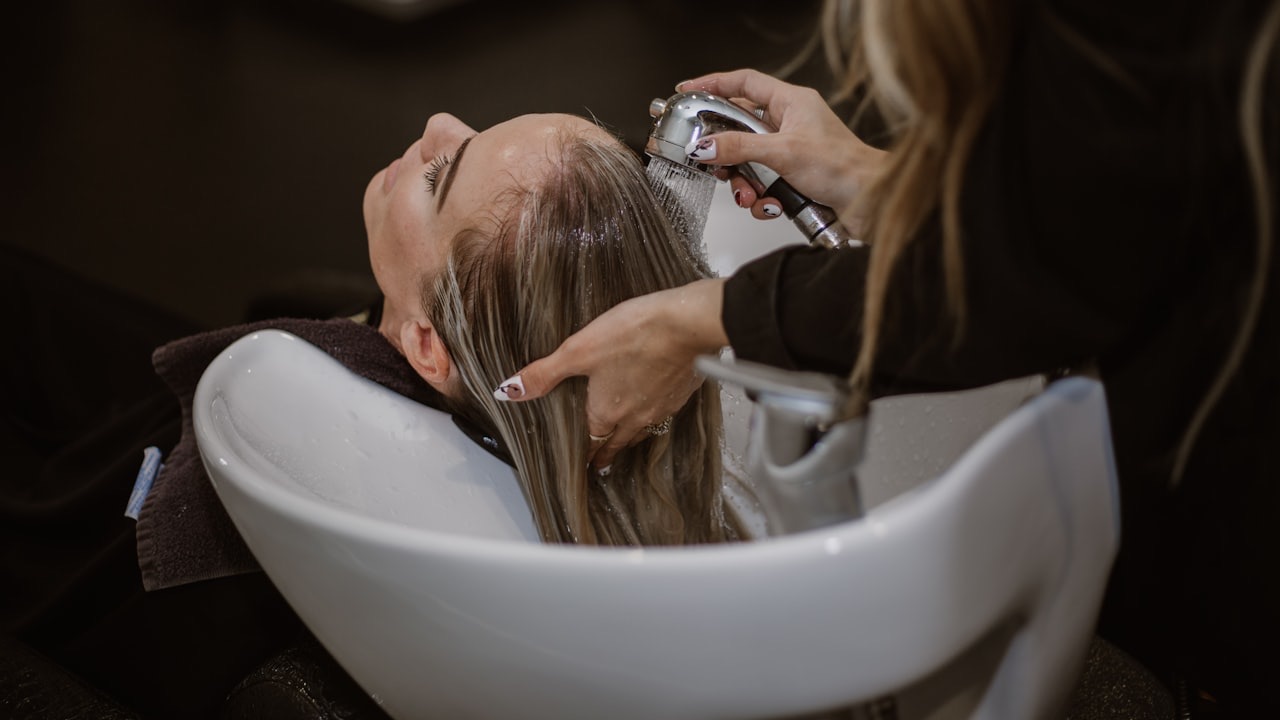 A hair stylist washing a client's hair at the salon basin