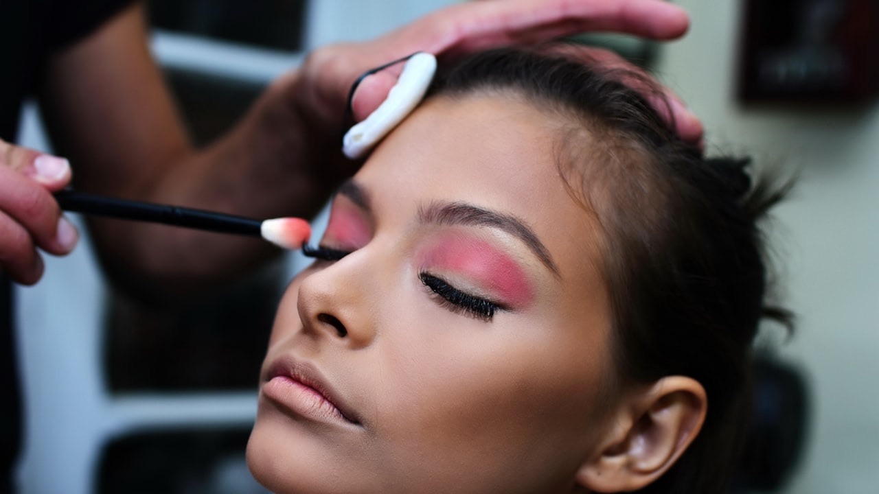 A makeup artist applying eyeshadow to a client with a brush
